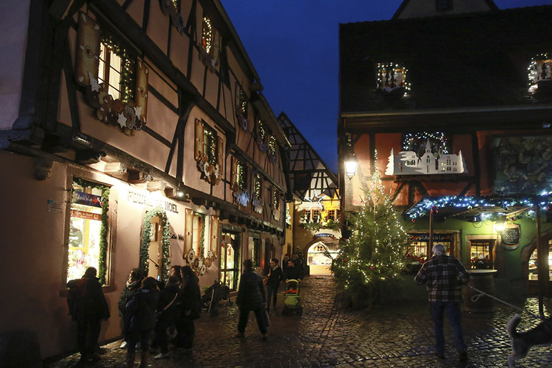 Village alsacien décoré pour Noël avec guirlandes lumineuses et maisons à colombages la nuit